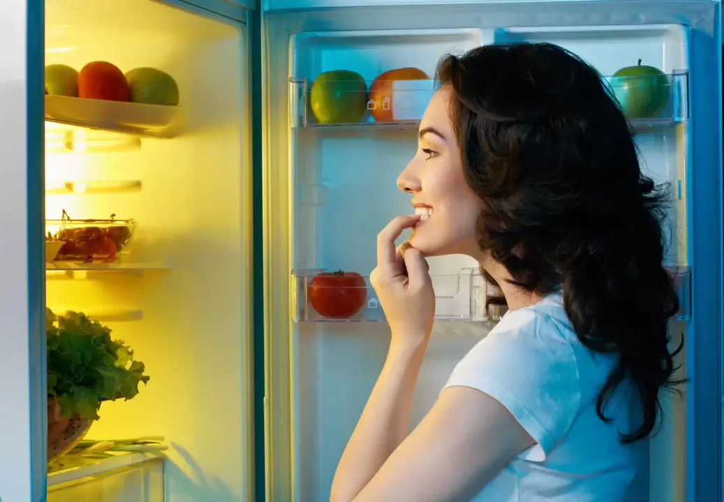 la fille regarde dans le réfrigérateur pendant une perte de poids rapide